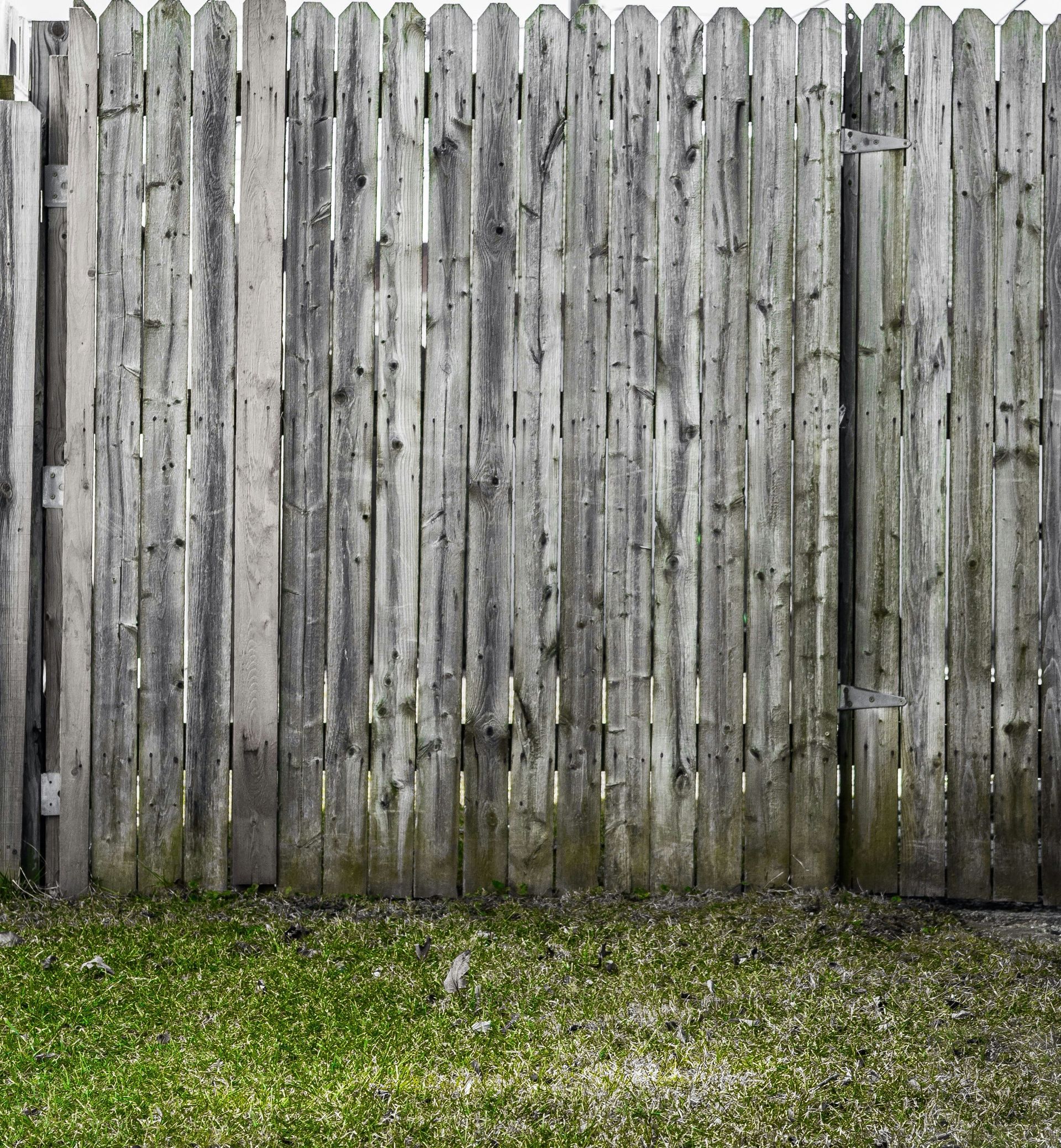 a wooden fence with grass in front of it